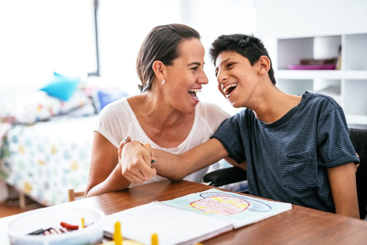 A support worker and a smiling young man sharing a laugh at home